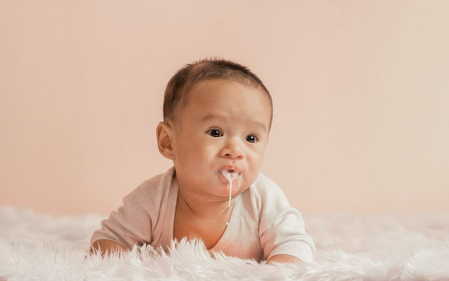 Why do newborn babies spit up or vomit milk after feeding?